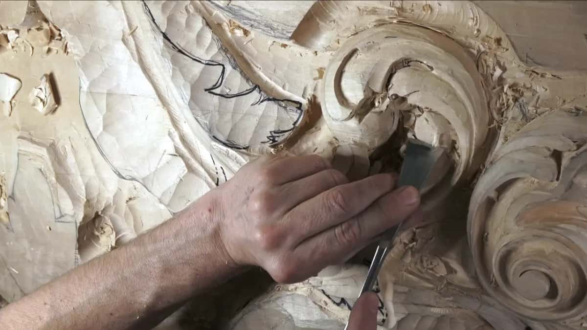 A narrower gouge reaching deep into the curl, the hand coming in from the left.