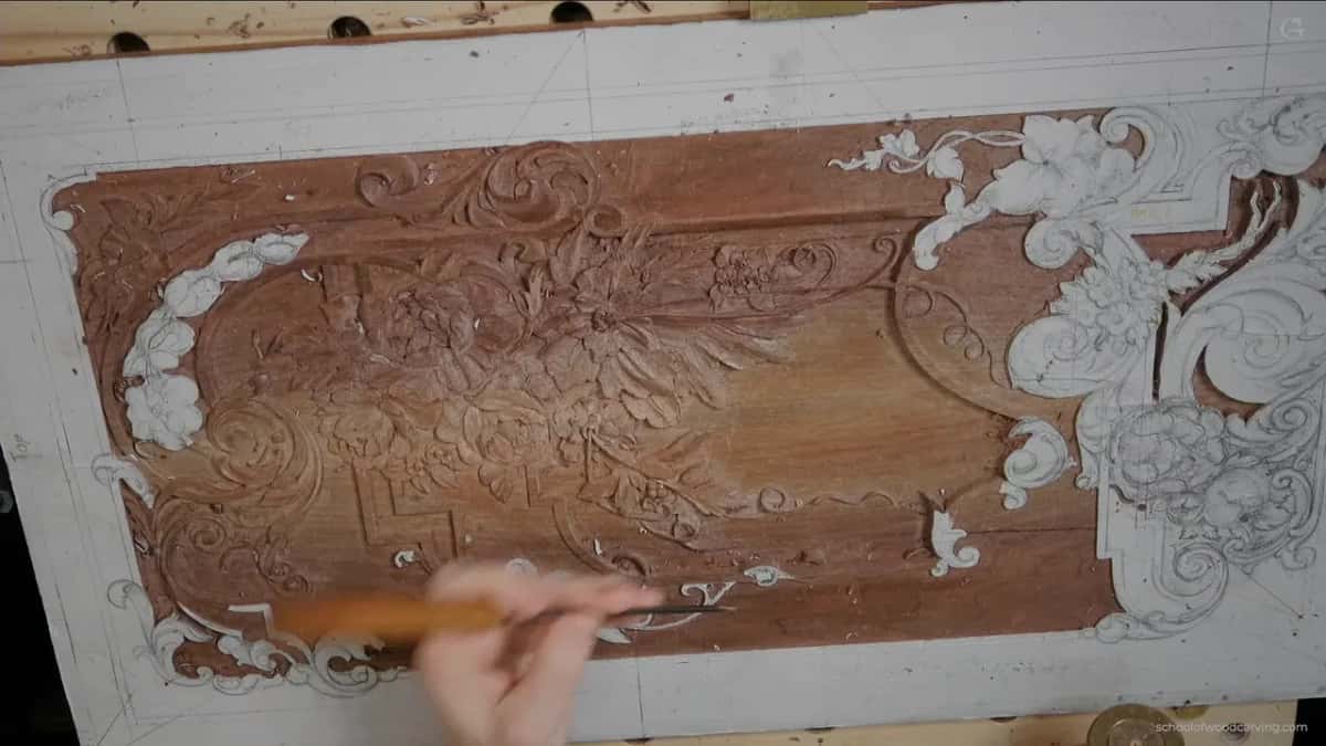 Top view of the walnut panel, the carved middle and white paper scrolls still glued at one end