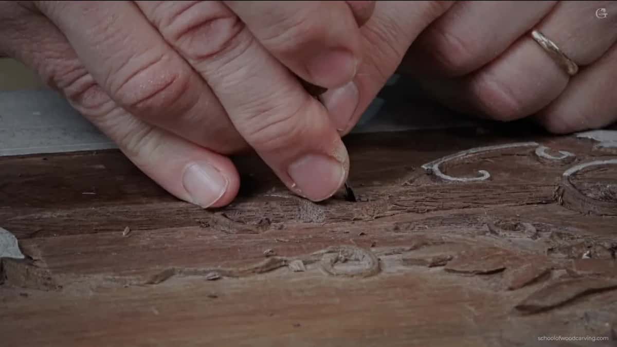 Two hands close together, a ring on one, tool point down in the chips