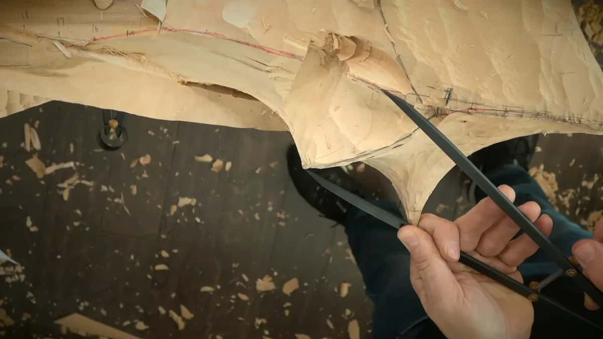 Outside calipers with bowed legs span the edge of the block, gripped in both hands