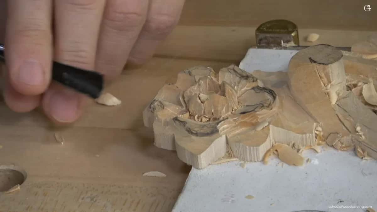 Hand pinching a short black tool, a chip dropping.