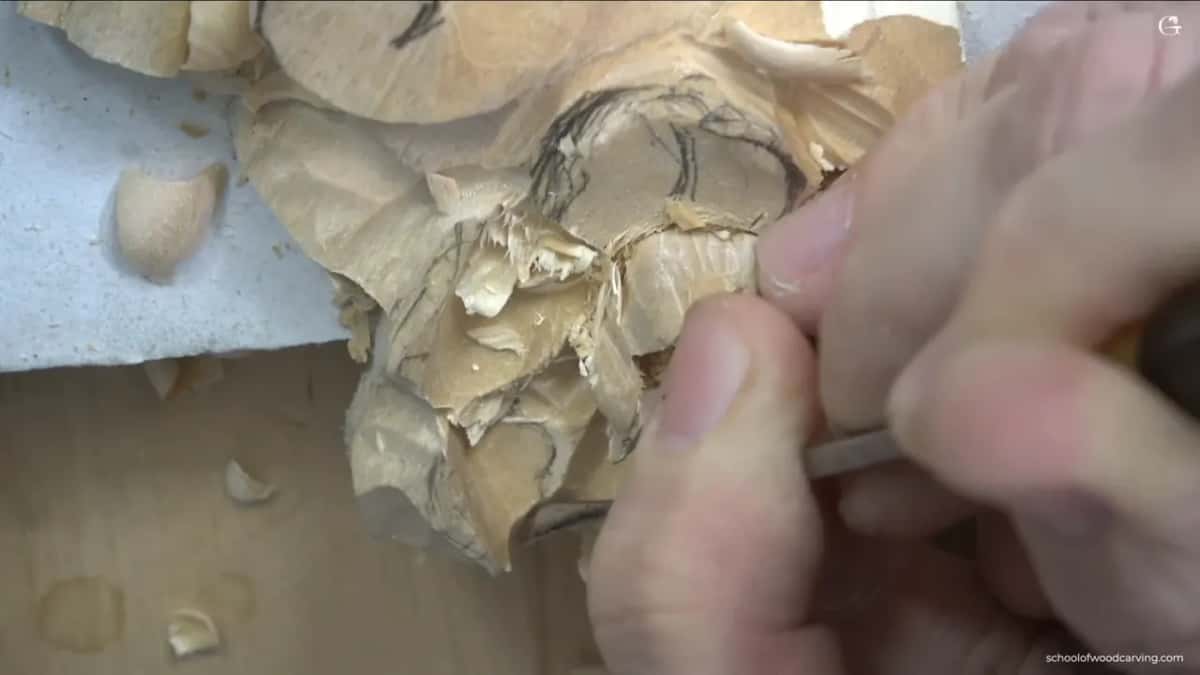 Fingers at the right of the flower holding a tool among loose chips.