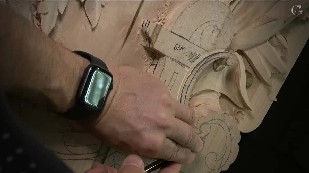 A wrist with a black watch, the tool held low inside the curve of the volute