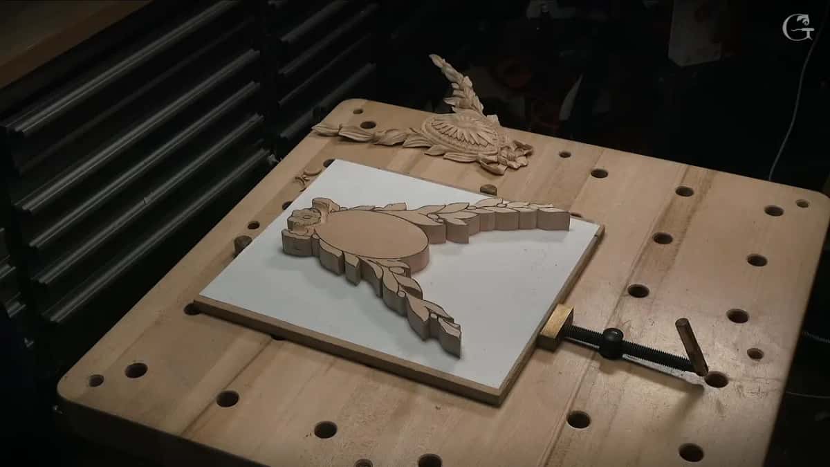 Carved rosette at the back of the bench, its mirror twin still a flat blank on the white board