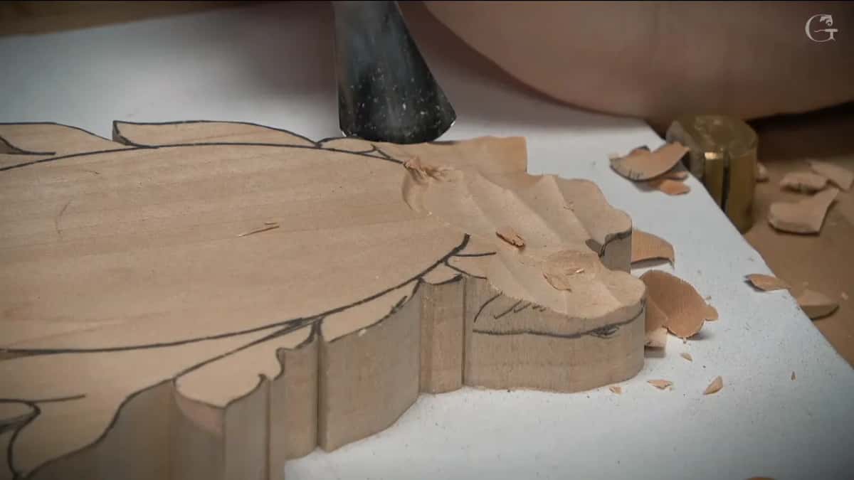 Gouge at the top edge of the blank, scooped grooves beside it and chips on the white board