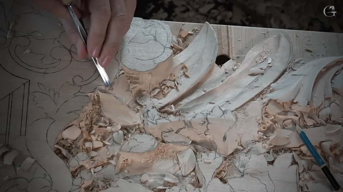 Fingertips hold a narrow tool on a pencil line near the leaves