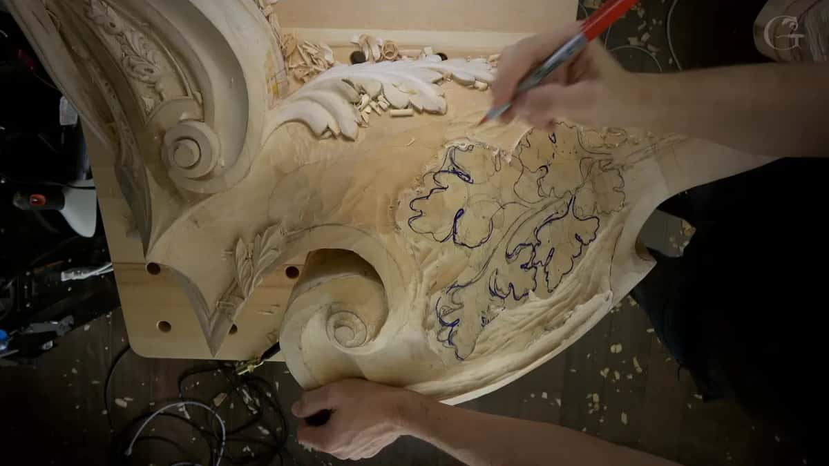 Red marker lifted over two leaves already outlined in blue, a carved scroll below