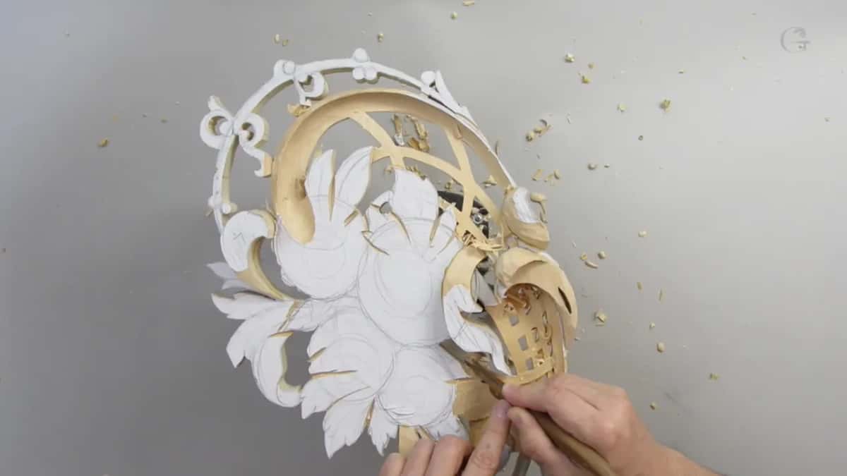 Two hands down at the lower edge of the panel, where the flowers are still under paper