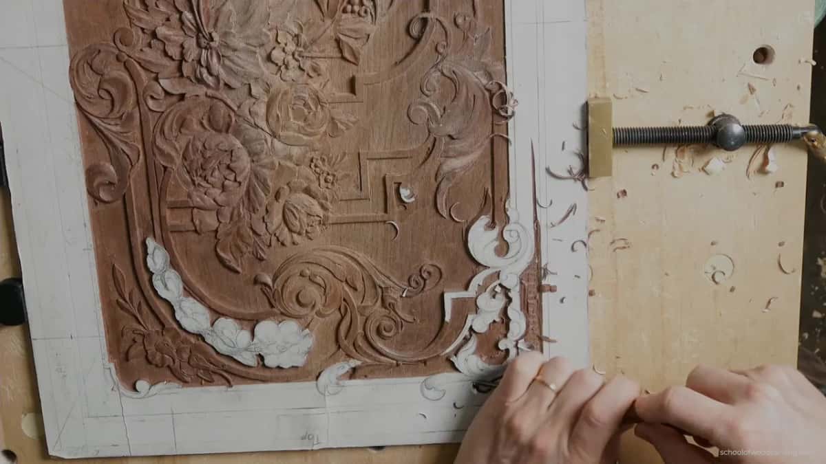 Two hands low on the board, a small tool at the corner scroll