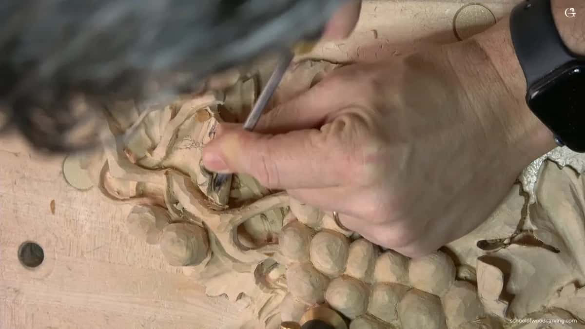 Slim tool along the vine, the carver's head blurred at the top
