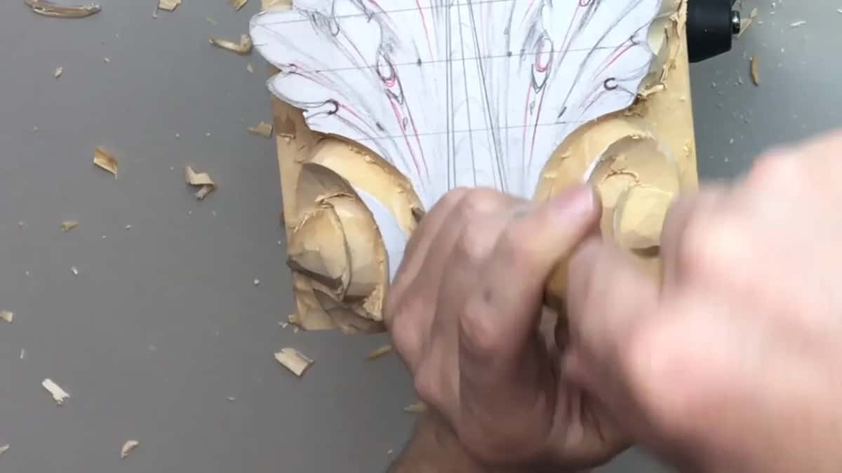 Two hands on one gouge by the right volute