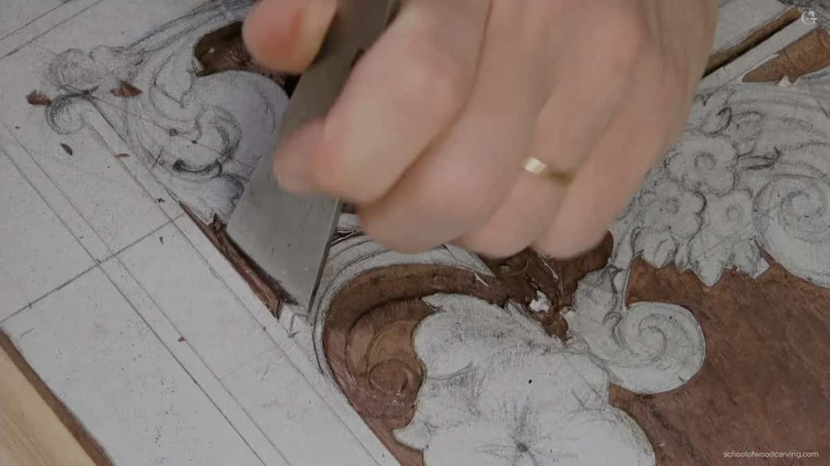 Wide flat chisel in my hand above a carved scroll