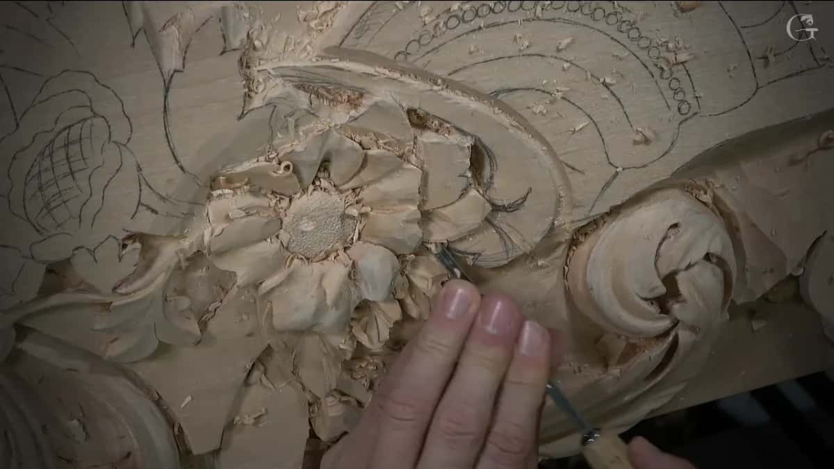 Fingertips holding a thin veiner right at the dark gap between a petal and the scroll