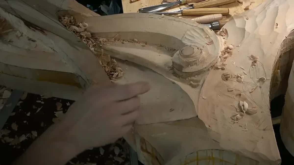 Low side view of the volute, an open hand along the flank and chips in the groove above