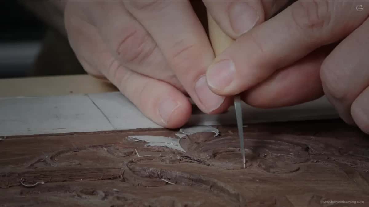 Knife held upright between two hands, its point resting on the carving near the molding