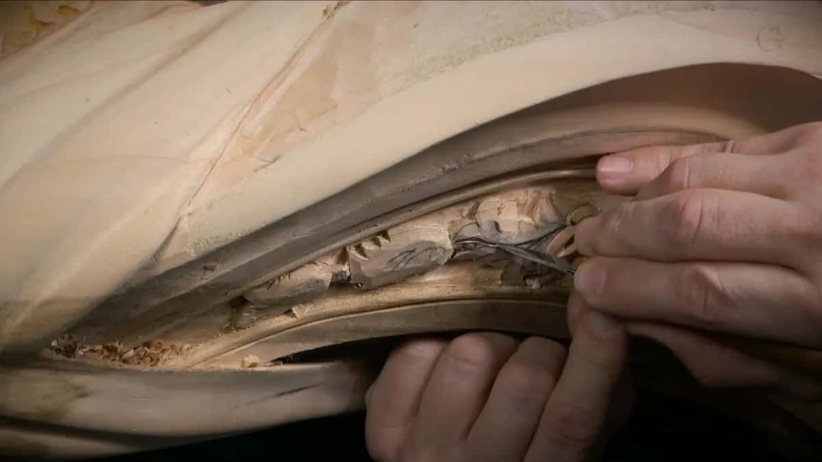 A small blade pressed against a tiny leaf being carved, both hands close