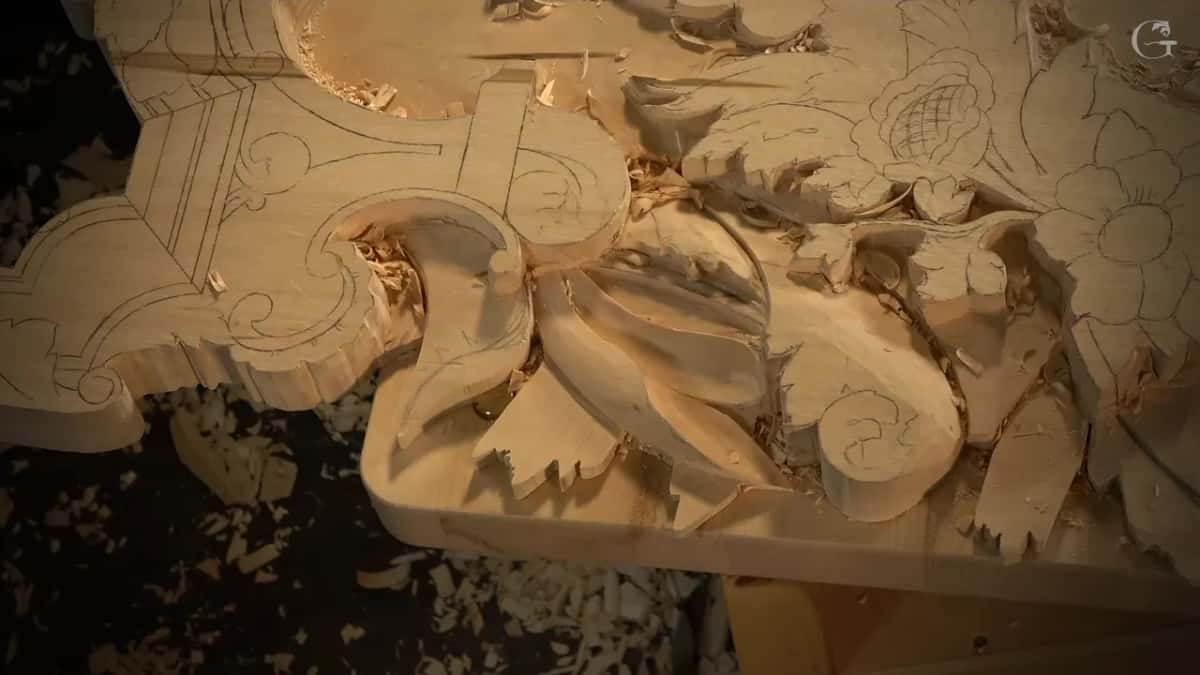 Seen from an angle, the carved leaves stand up off the board with shavings on the floor beneath