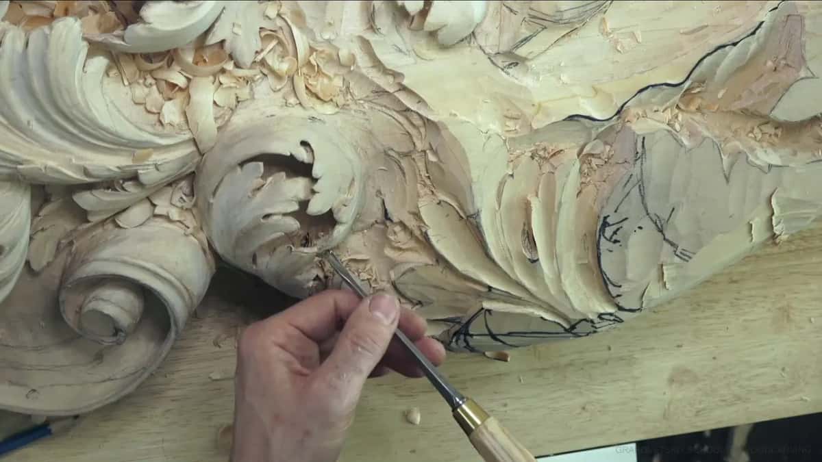 Thin gouge, brass ferrule, slanting into the curl of the scroll from one hand.