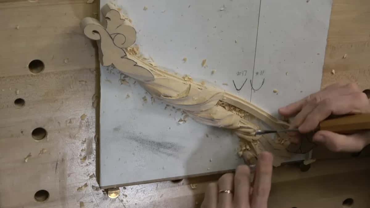 Top camera, the tool at the flower end and the other hand flat on the board below it.