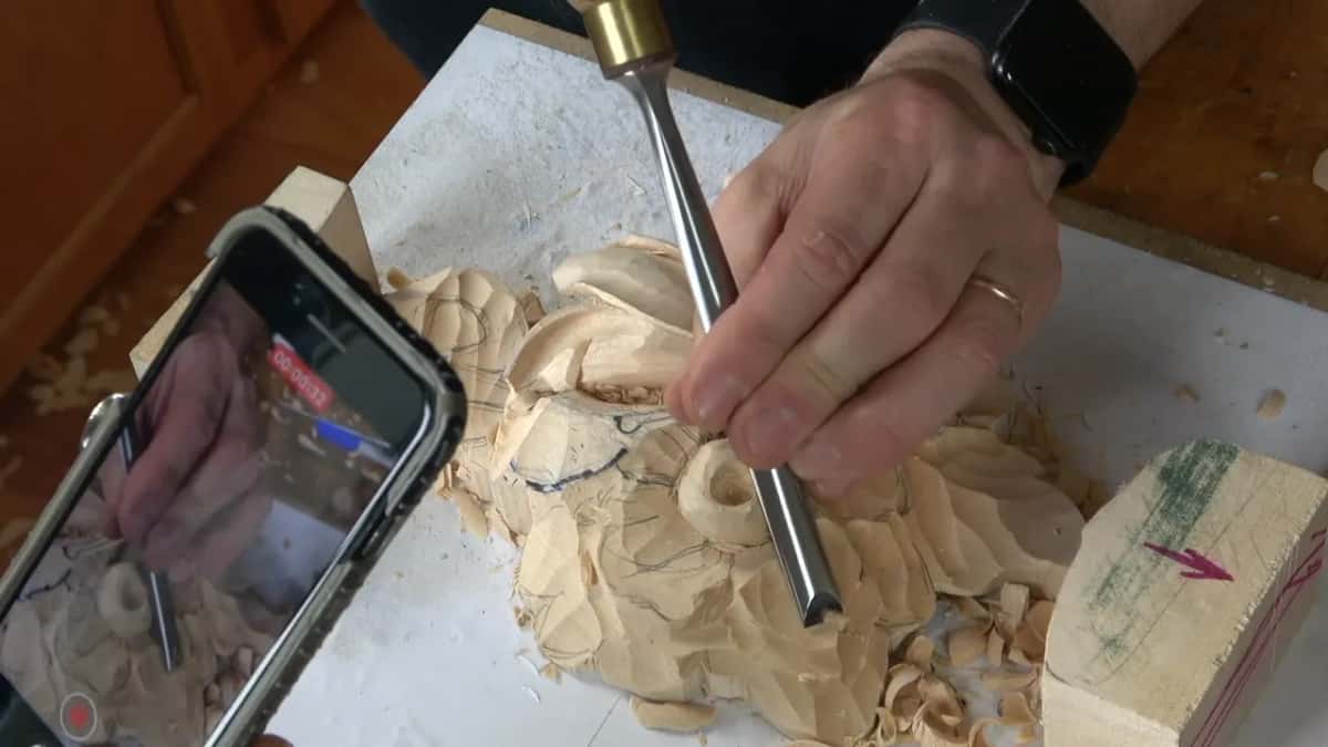 A phone in front of the bench, recording, while the gouge carries on working