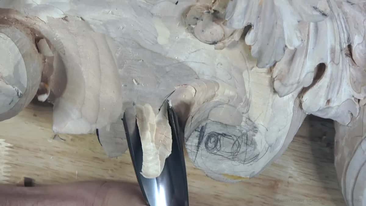 A wide, shiny gouge chops down at the edge of the block while the pencil spiral waits beside it for its turn.