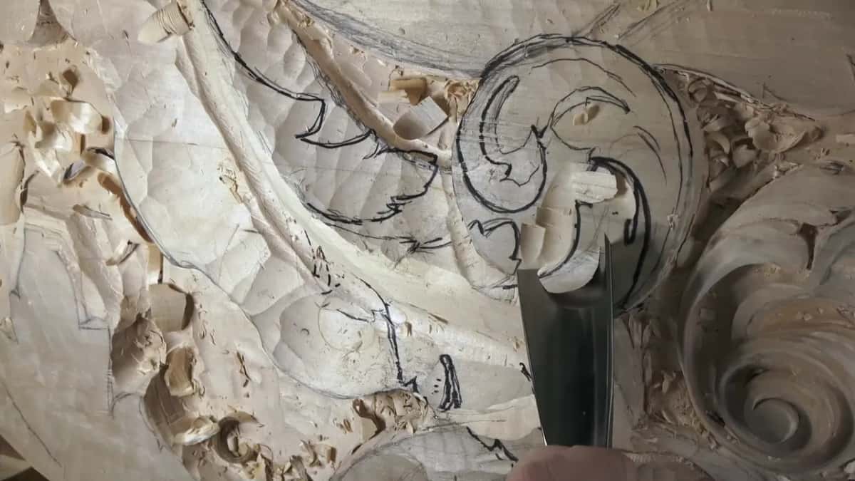 A wide flat gouge bites into the drawn scroll while black marker lines still show.