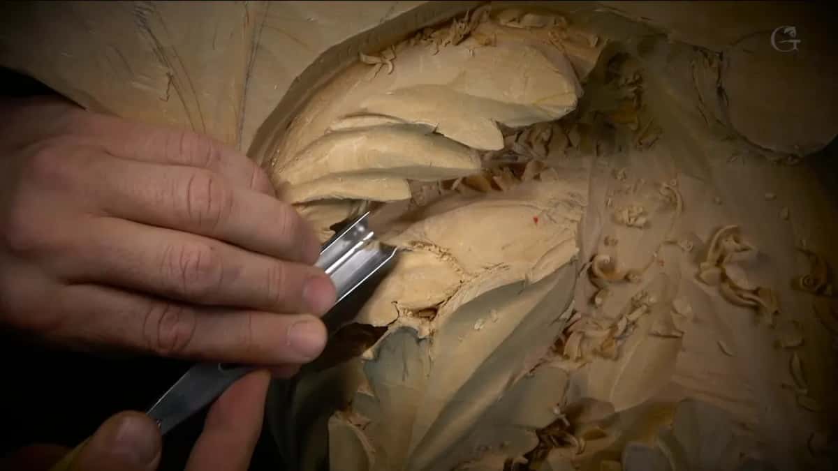Broad steel blade under two fingers, working the edge of a leaf