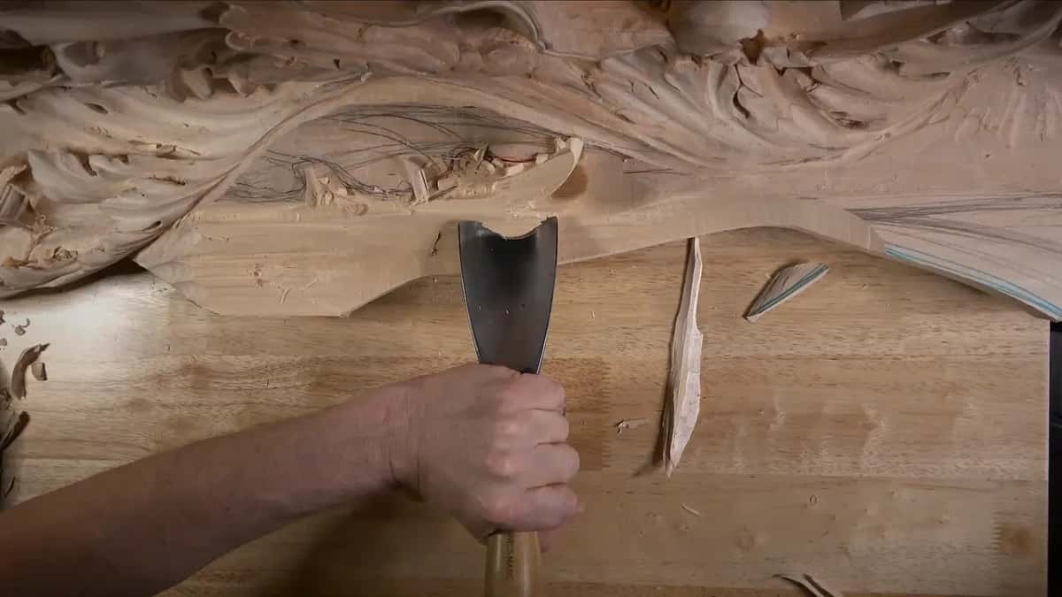 Wide gouge standing upright next to a splinter lying on the bench, the slope roughed out behind it
