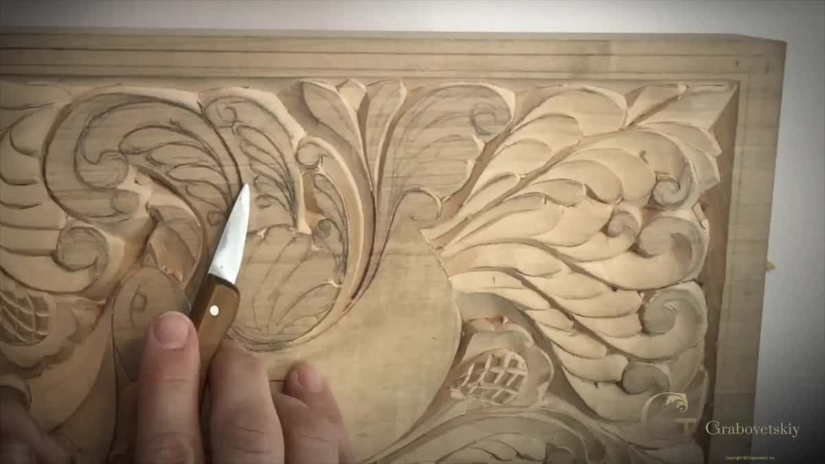 Small knife held upright among the pencil lines of the wing, a thumb under its handle