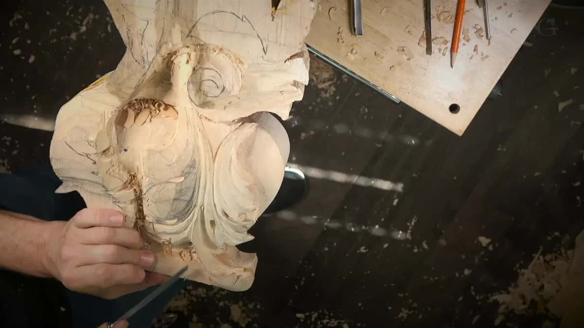 Left hand grips the block while a thin tool works along its lowest edge