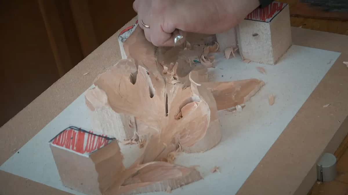 Curled shavings pile up where a fist works the far end of the leaf, the tool almost hidden in the hand