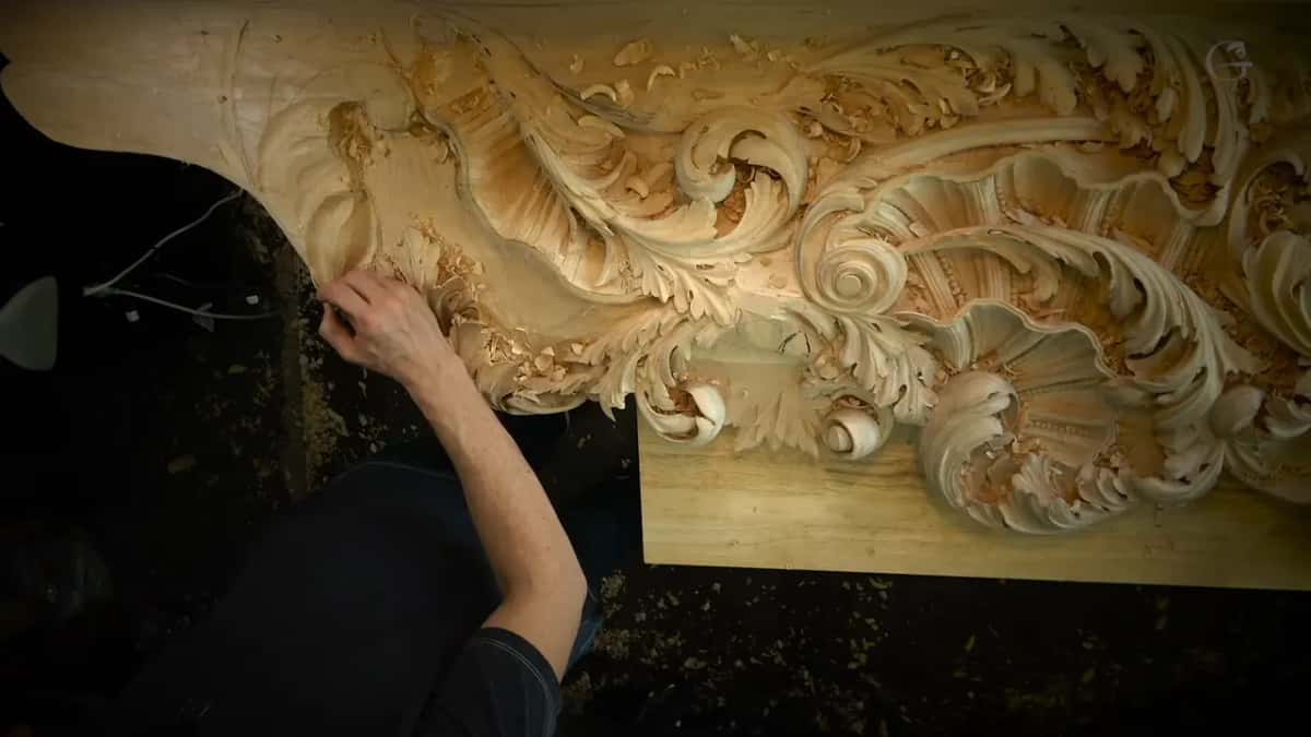 The board from above Looking down on the full board, scrolls and shell forms already carved, one arm reaching in from the left