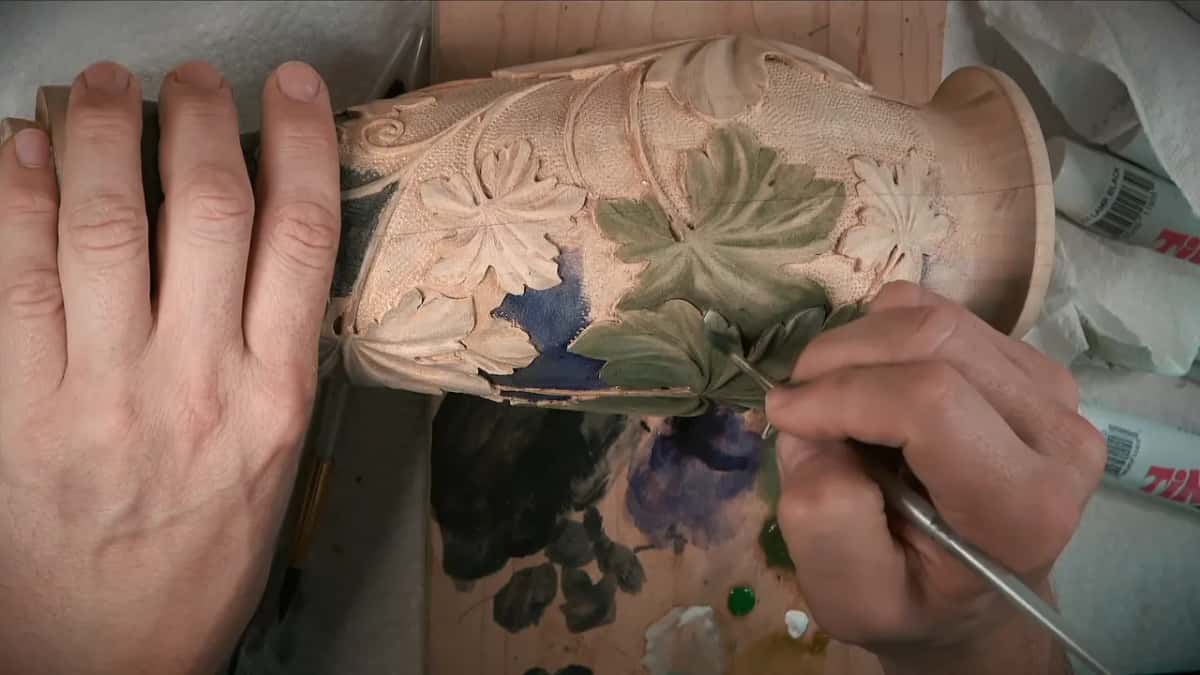 Fine tip touching the end of a lower leaf, right next to its stem, with one hand flat on top