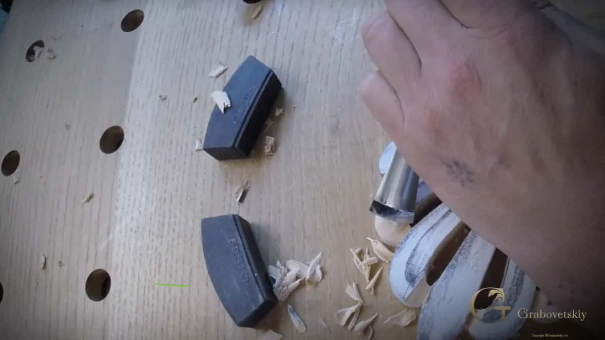 Fresh chips pile up beside two black stops as the gouge works the end of a lobe.