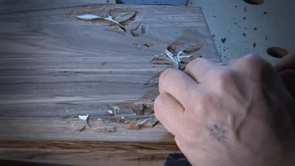 Small gouge working a leaf on a dark board, chips lifting off
