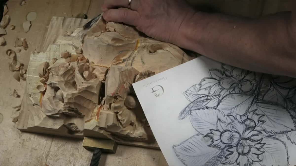 The paper pattern of the hazelnuts lies beside the panel while one hand rests on the block