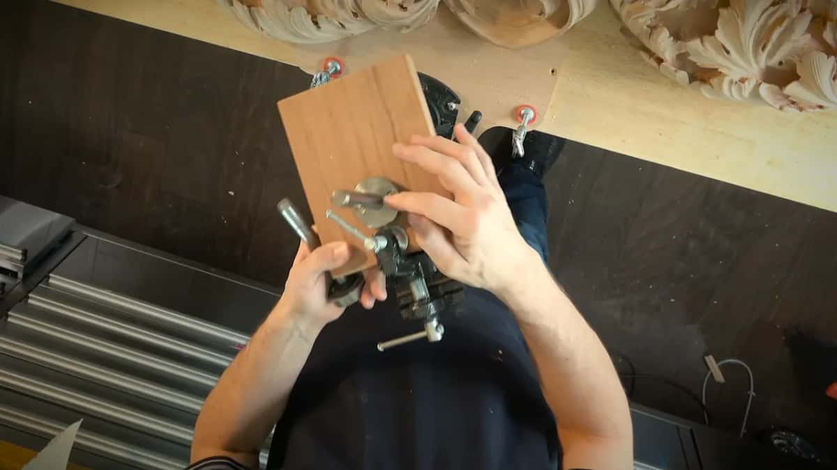 Both hands set the plated block onto a vise