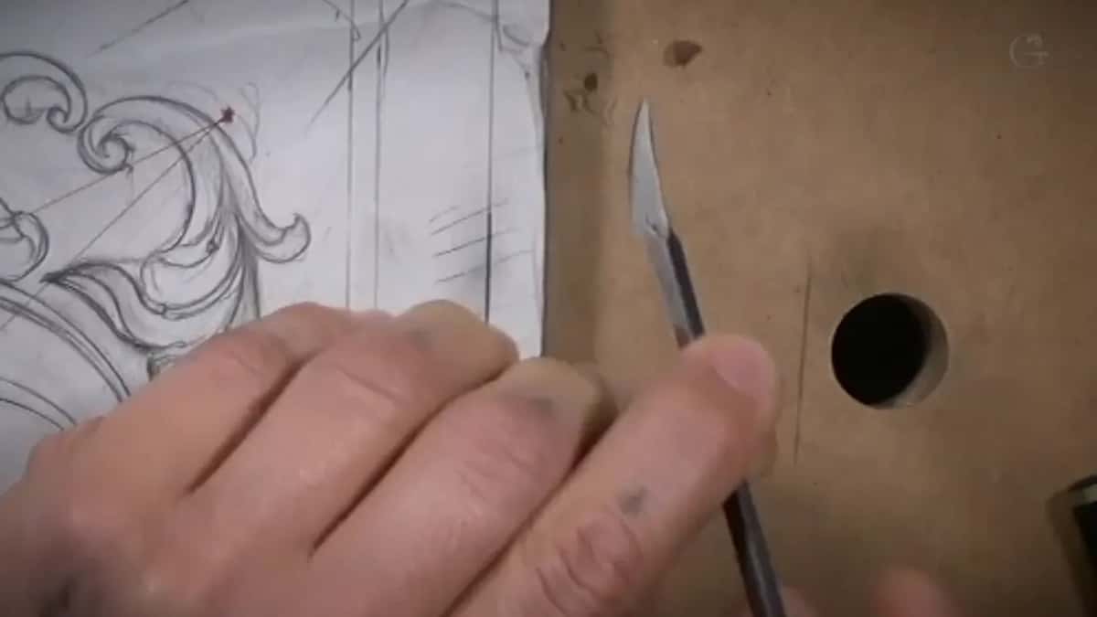 A knife rests beside the drawing, one hand on the paper.