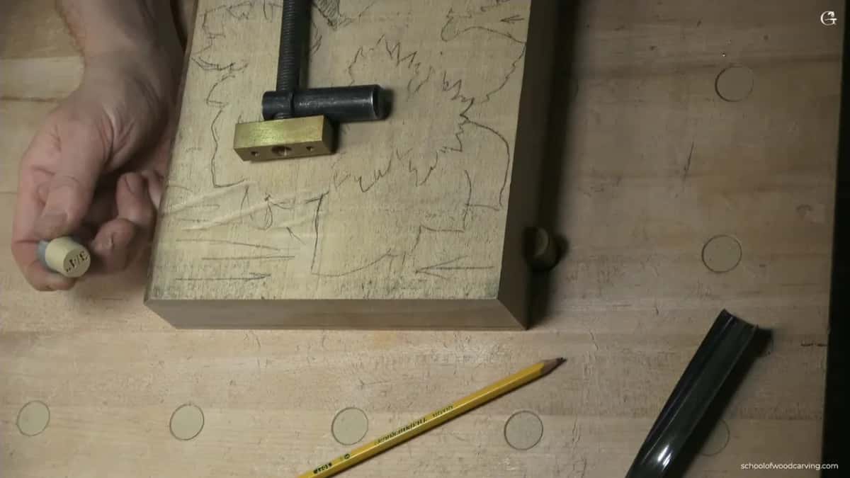 Brass faced screw clamp on the drawn hazelnut block, a hand holding a small round piece.