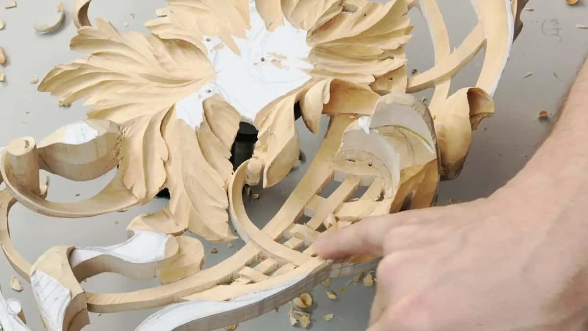 A fingertip runs along the carved lattice, beside a fan of leaves and a few loose chips.