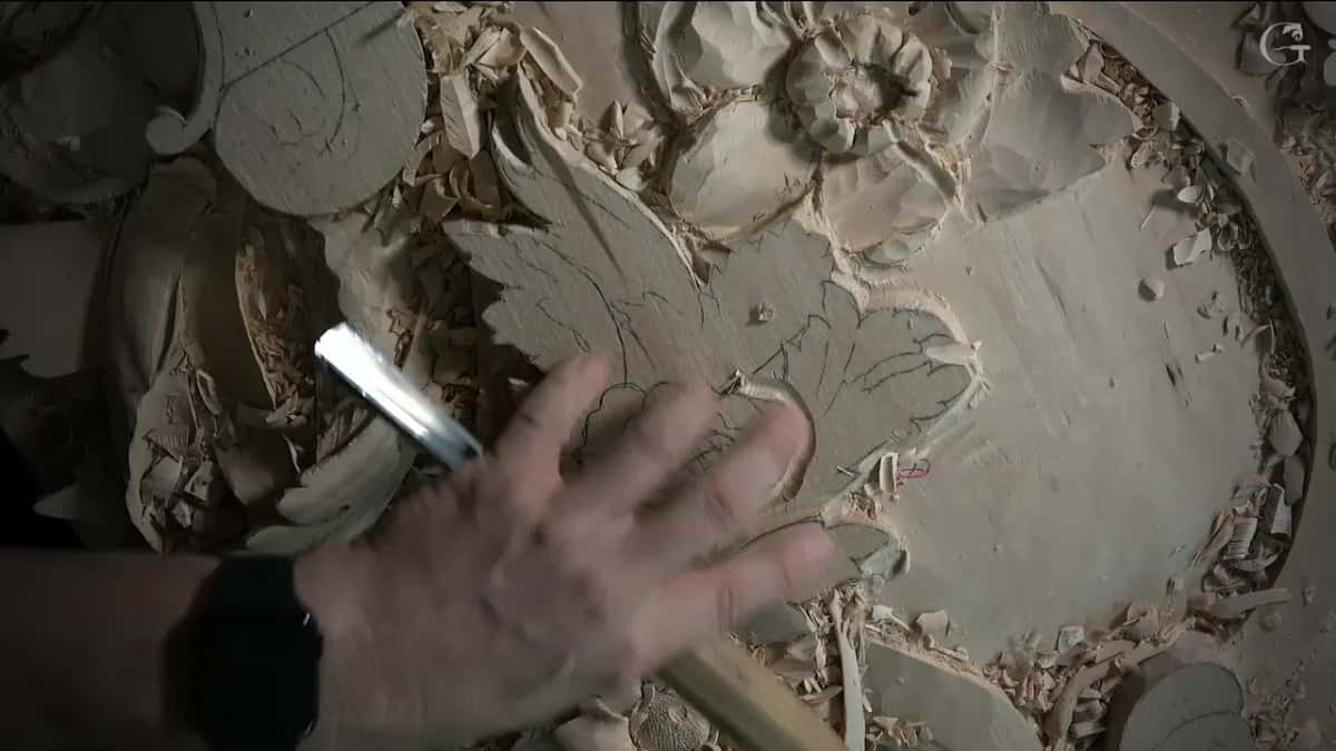 Hand and chisel near carved flower