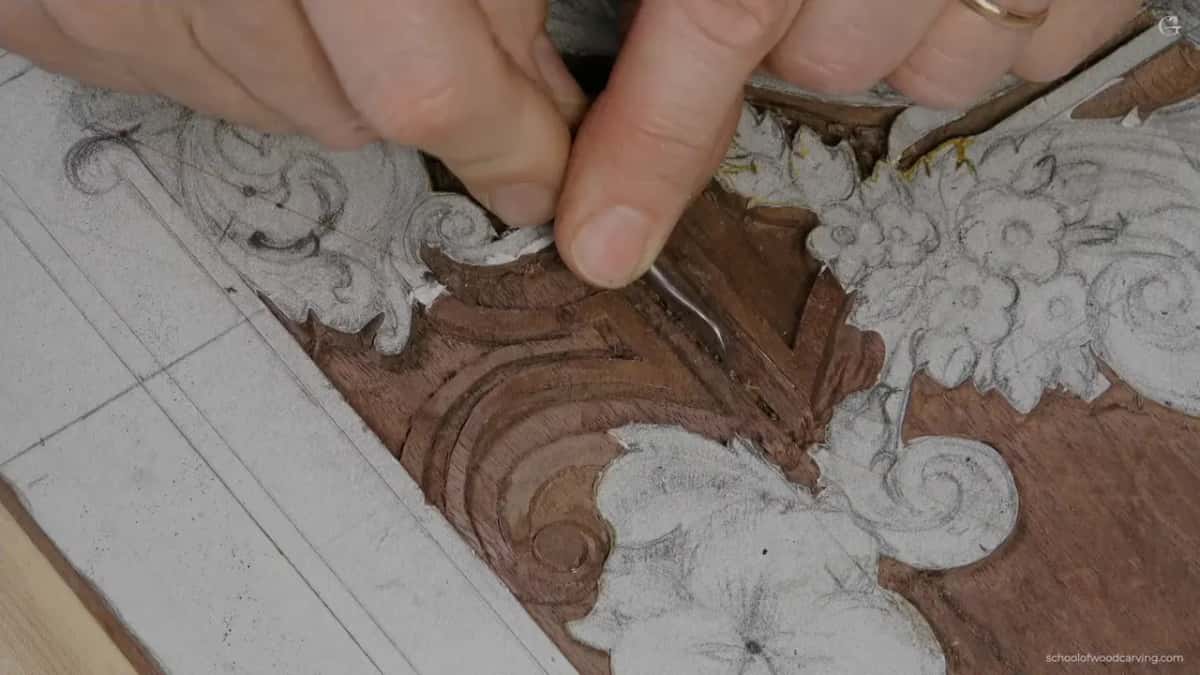 Paper pattern on dark wood, a gouge tip at its edge