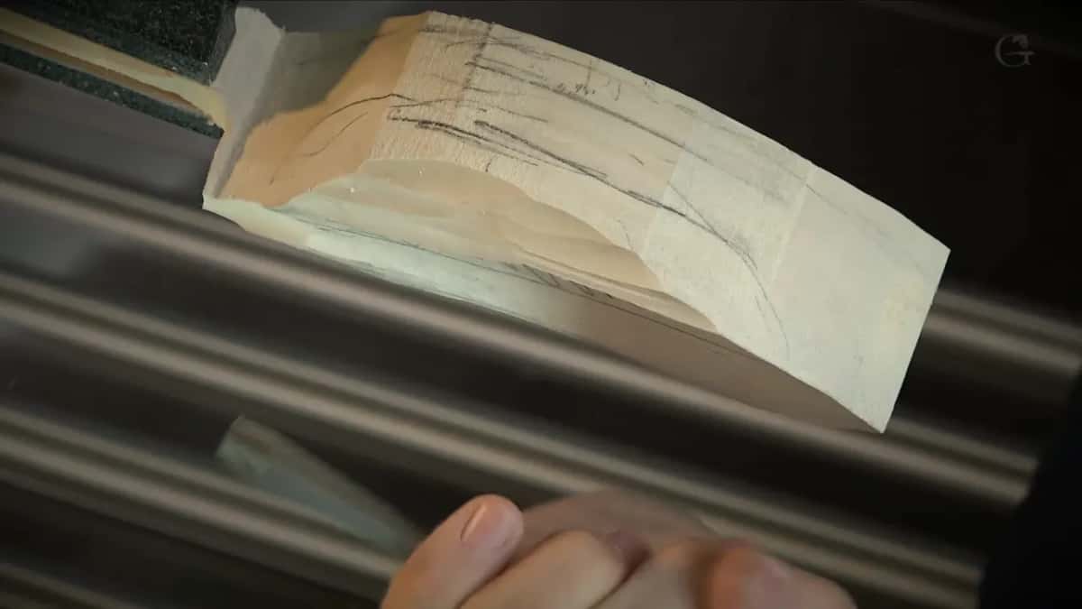 Long pencil marks run along a pale block held up above steel drawers