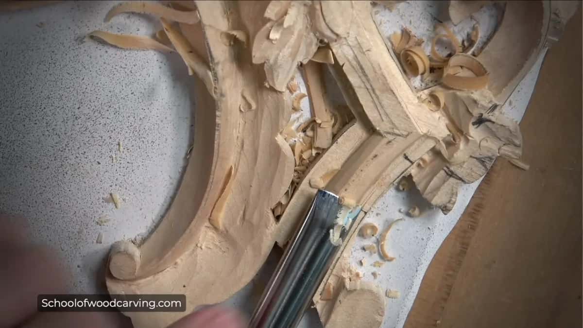 Straight-shanked gouge working down the molding, small curled shavings all around it