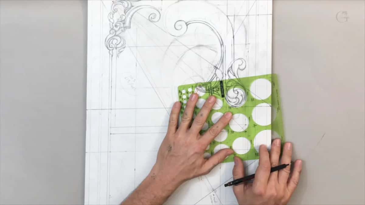 Green plastic template of round holes pressed flat on the drawing, a pen in the other hand
