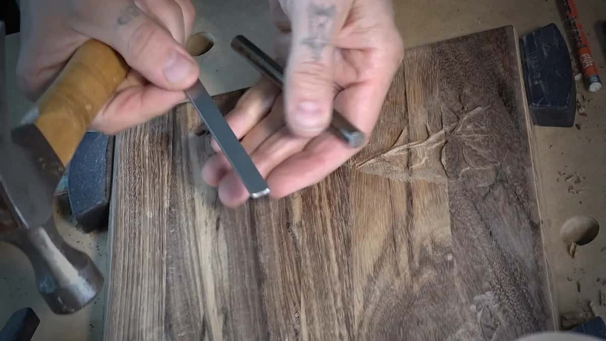 Hammer in one hand, a rectangular punch and a round one in the other