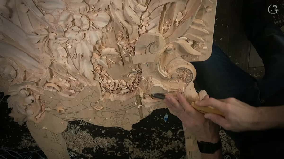 Overhead view of the hand carved Venetian panel, with a small gouge working at its lower edge