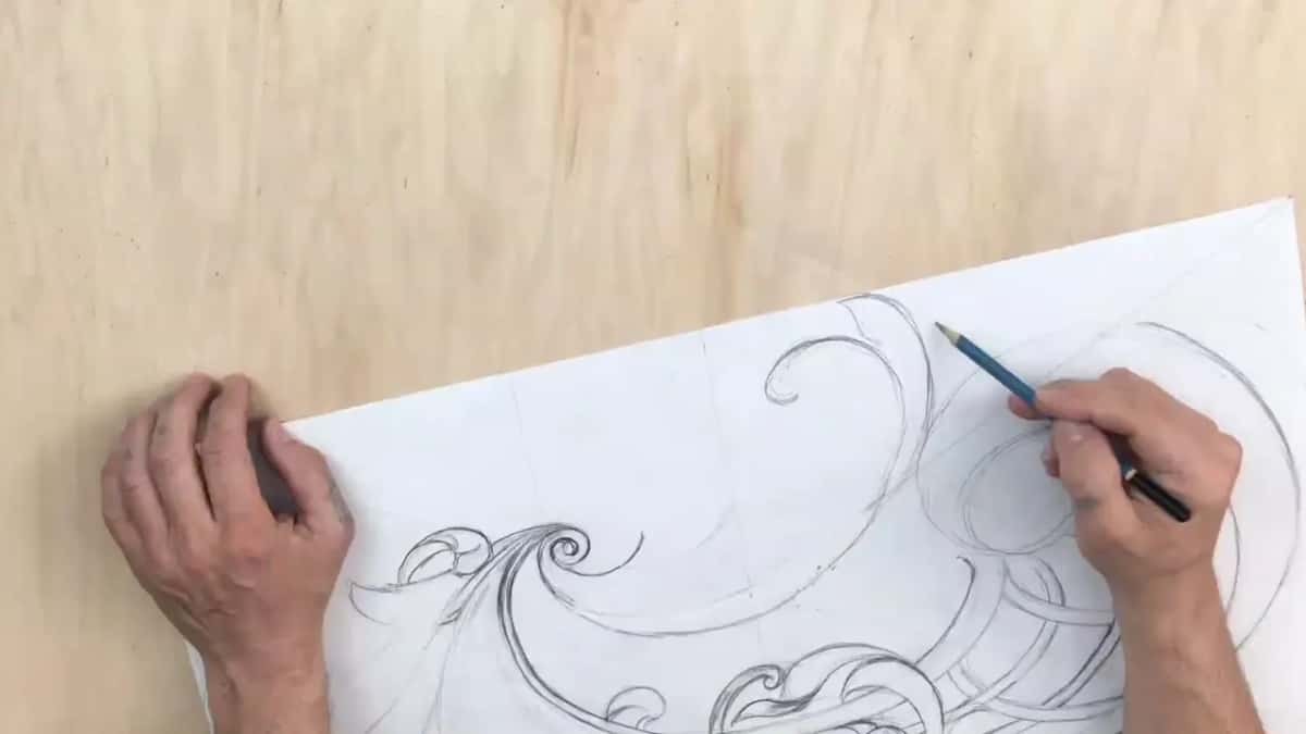Long pencil curves sweep past a ring as the left hand steadies the turned sheet
