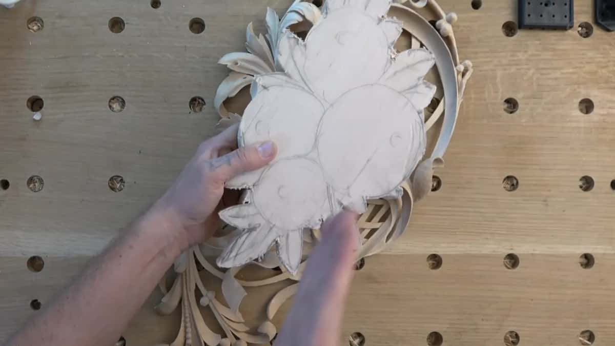 Second layer blank with its flower rings drawn, set onto the carved first layer on a bench full of dog holes