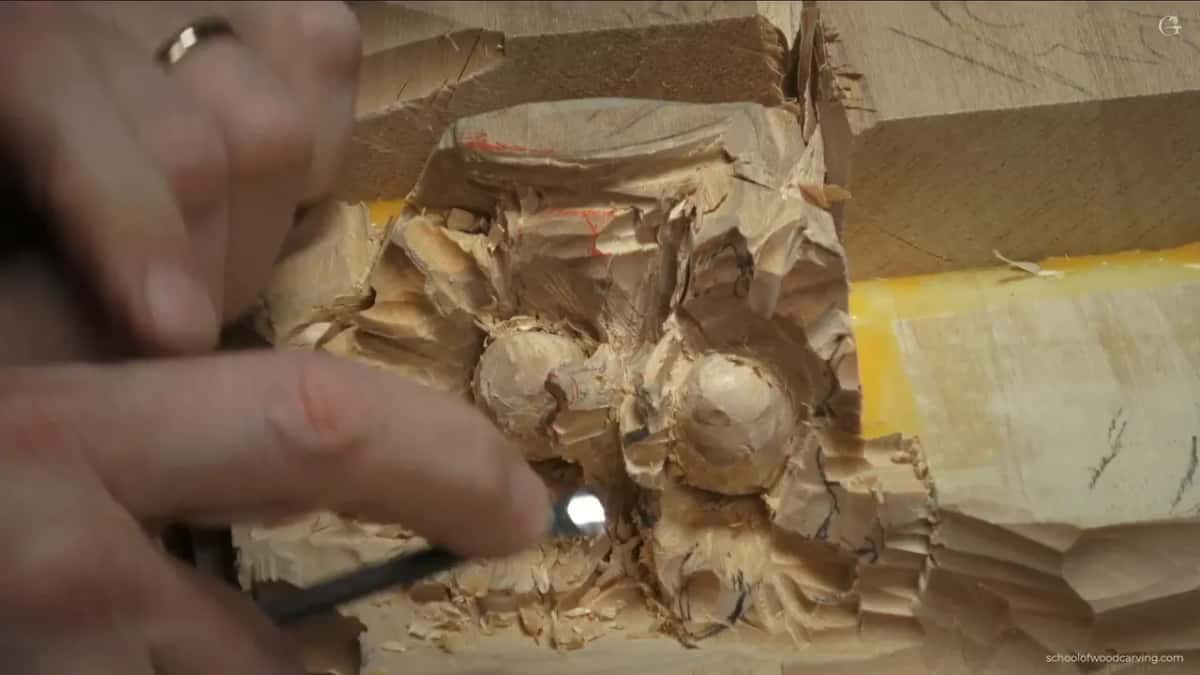 Fingers bracing a small tool under a hazelnut husk